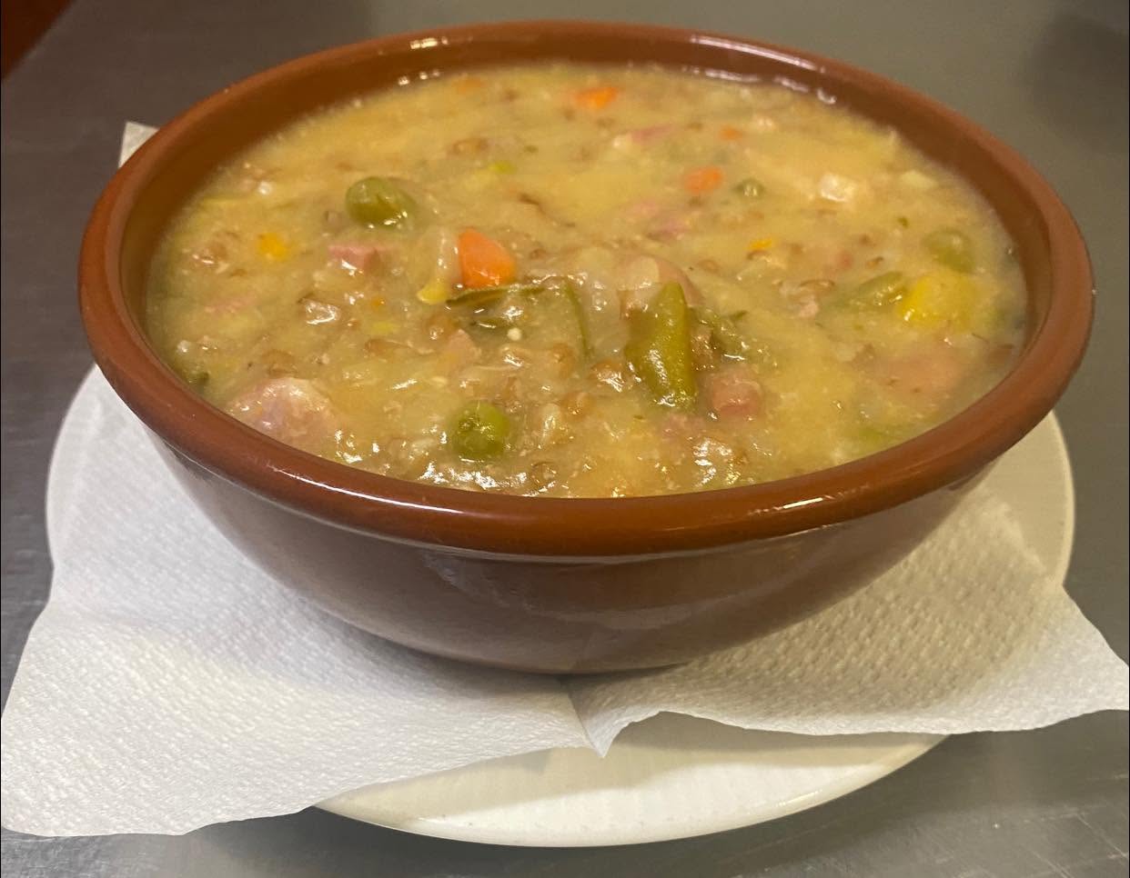 Hearty bean and vegetable soup in a terracotta bowl