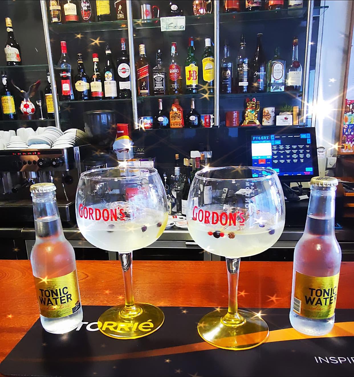 Two gin and tonics at the bar with bottles of tonic water